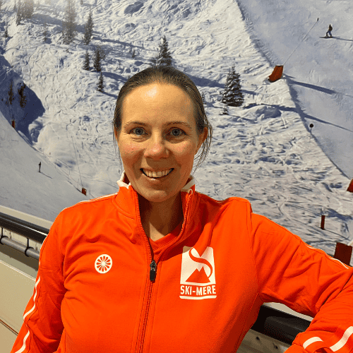 - Ski-instructeur lachend met skigebied op de achtergrond tijdens indoor skiles in Almere.