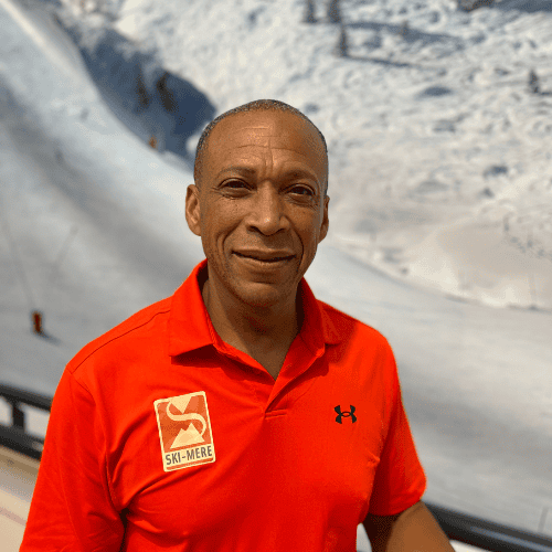 Ski-instructeur in de indoor rolpiste in Almere met sneeuw op de achtergrond.