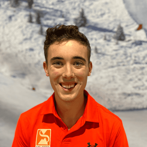 Jonge man in rood ski- of snowboardoutfit met glimlach voor een winters achtergrond.