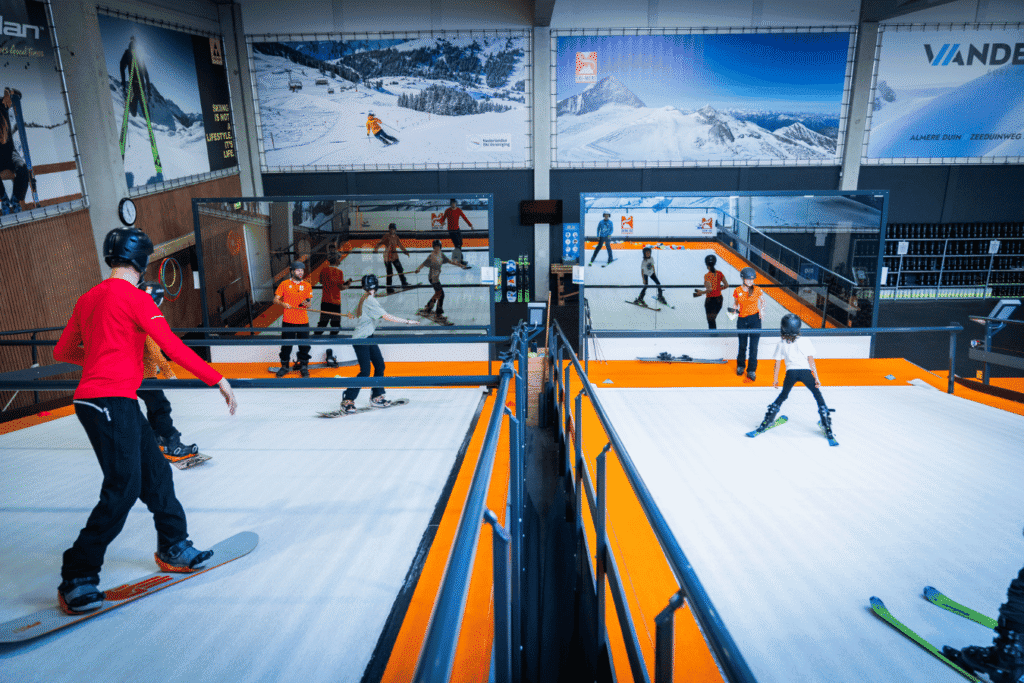Skimiré indoor ski- en snowboardhal in Almere met kinderen en volwassenen die leren skiën en snowboarden.