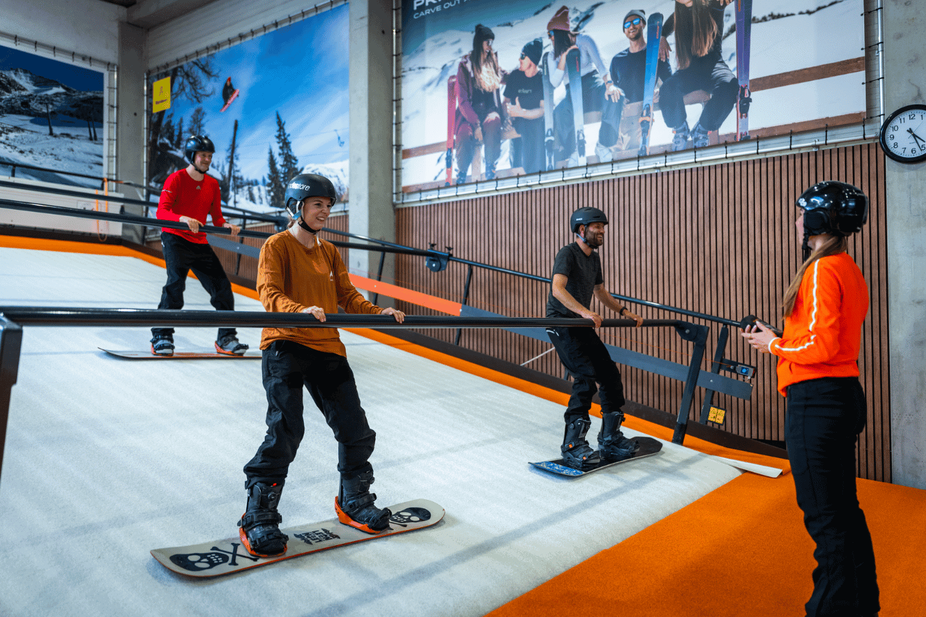 Snelle, jonge skiërs op de indoor rolpiste in Almere met instructeur die tips geeft.