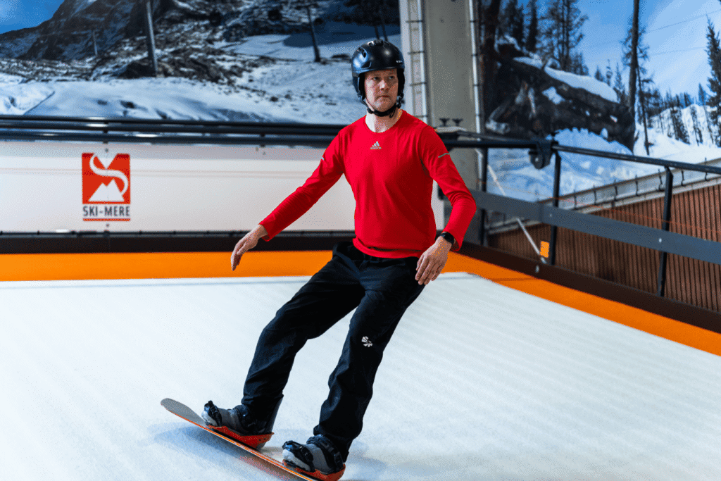 Skibestuurder op indoor rolpiste in Almere met bergen en bergen in de achtergrond.
